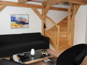 ブラーバンドにある5 person holiday home in Bl vandのリビングルーム(黒いソファ、木製の階段付)