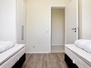 Ce lit se trouve dans un dortoir doté de murs blancs et de parquet. dans l'établissement Two-Bedroom Holiday home in Großenbrode 11, à Großenbrode