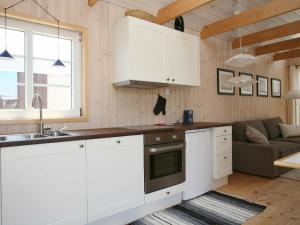 a kitchen with white cabinets and a couch in a room at 4 person holiday home in Karreb ksminde in Karrebæksminde