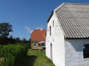 a white building with a red roof and a yellow house at 6 person holiday home in Skagen in Hulsig