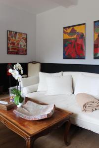 a living room with a white couch and a wooden table at Hôtel Les Empreintes in Saint-Évarzec