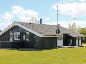 a small black house with a grass yard at 6 person holiday home in Hadsund in Øster Hurup