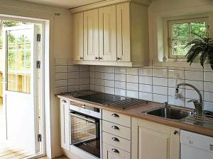uma cozinha com armários brancos e um lavatório em 4 person holiday home in VIKBOLANDET em Arkösund