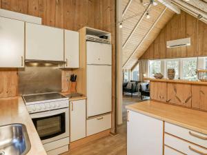cocina con electrodomésticos blancos y paredes de madera en 8 person holiday home in Bl vand en Blåvand
