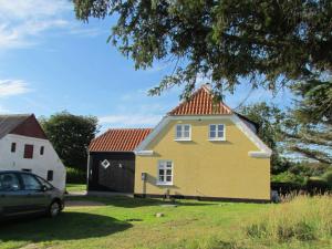 a yellow house with a red roof next to a car at 6 person holiday home in Skagen in Hulsig