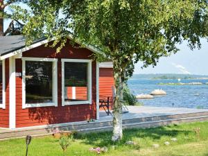 una casa roja con un banco frente al agua en 2 person holiday home in SÖLVESBORG-By Traum, en Björkenäs