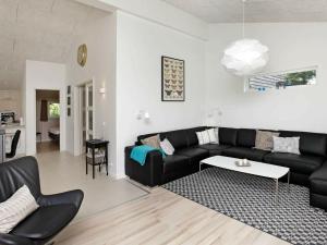 a living room with a black couch and a table at 10 person holiday home in Bl vand in Blåvand