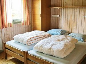 two beds with white blankets on top of them in a room at Four-Bedroom Holiday home in Væggerløse 18 in Marielyst