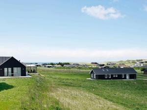 a black house in a field with buildings at Three-Bedroom Holiday home in Løkken 40 in Løkken