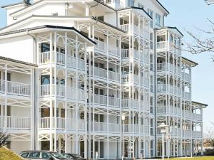 ein weißes Gebäude mit Balkonen und davor geparkt Autos in der Unterkunft Two-Bedroom Holiday home in Großenbrode 4 in Großenbrode