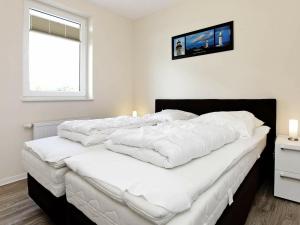 グローセンブローデにあるTwo-Bedroom Holiday home in Großenbrode 10の白いシーツを使用した大きなベッド、窓が備わります。