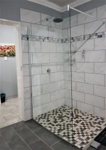 y baño con ducha y puerta de cristal. en Graceland Guesthouse, en Potchefstroom
