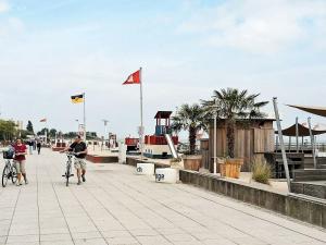 two people riding bikes on a pier with flags at One-Bedroom Holiday home in Großenbrode 2 in Großenbrode