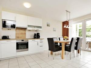グローセンブローデにあるOne-Bedroom Holiday home in Großenbrode 2の白いキャビネット、テーブルと椅子付きのキッチンが備わります。