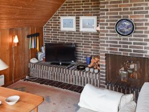 a living room with a brick wall with a flat screen tv at Holiday home Hvide Sande VIII in Havrvig