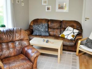 a living room with a brown leather couch and a coffee table at 5 person holiday home in ARVIKA in Arvika