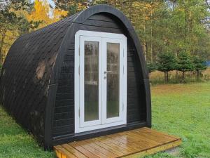 a black iguana house with a white door in a field at 6 person holiday home in R dby in Rødby