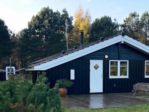 a black building with a white door and a porch at 6 person holiday home in R dby in Rødby