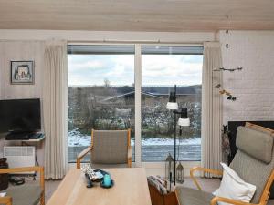 een woonkamer met een tafel en een groot raam bij Holiday home Hirtshals III in Hirtshals