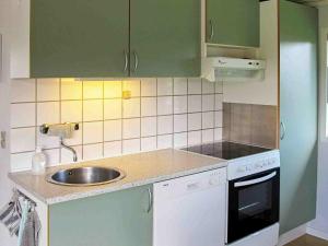 een keuken met groene kasten en een wastafel bij 6 person holiday home in Str by in Strøby
