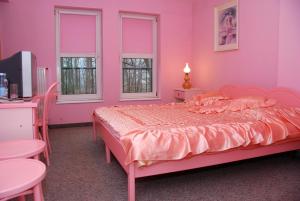 a pink bedroom with a bed and two windows at Noclegi u Marii in Gorzów Wielkopolski