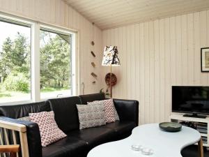 Mosevråにある10 person holiday home in Oksb lのリビングルーム(黒い革張りのソファ、テーブル付)
