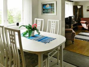una mesa de comedor blanca con 3 sillas y un jarrón de flores en 6 person holiday home in Brastad, en Brastad