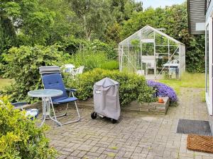 einen Garten mit einem Tisch, Stühlen und einem Gewächshaus in der Unterkunft 4 person holiday home in K ge in Strøby Egede