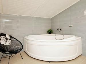 - białą wannę w łazience z krzesłem w obiekcie Holiday Home Monasvej w mieście Grønhøj
