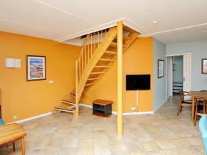a living room with a wooden staircase and a tv at 8 person holiday home in Bl vand in Blåvand
