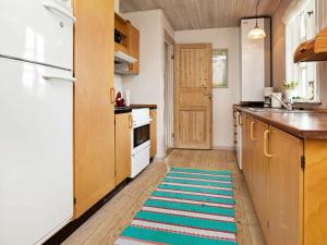 - une cuisine avec des placards en bois et un tapis au sol dans l'établissement Holiday Home Horns Rev III, à Blåvand
