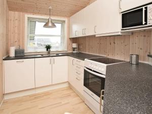 eine Küche mit weißen Schränken und einer schwarzen Arbeitsplatte in der Unterkunft 6 person holiday home in Hirtshals-By Traum in Hirtshals