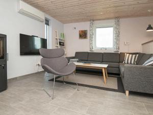 a living room with a couch and a table and a chair at Holiday home Henne IX in Henne Strand