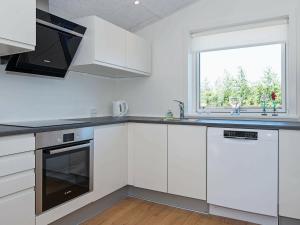une cuisine avec des placards blancs et une fenêtre dans l'établissement 6 person holiday home in L kken, à Løkken