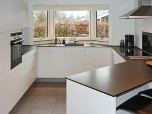 uma cozinha com armários brancos e um balcão preto em Holiday Home Brøndbækken II em Nørre Hurup