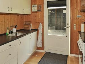 cocina con armarios blancos, fregadero y puerta en 6 person holiday home in Ansager, en Ansager