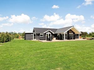 a black house with a large grass field at Holiday Home Hansavej in Marielyst
