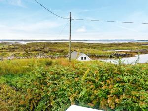 uma pequena casa branca no meio de um campo em 6 person holiday home in Dyrvik em Dyrvik