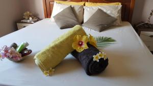 Una cama con dos toallas y flores. en Aux plaisirs de la vie en Flic-en-Flac