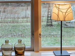 una lámpara y dos jarrones de cristal en un alféizar de la ventana en 8 person holiday home in Varg n en Västra Tunhem