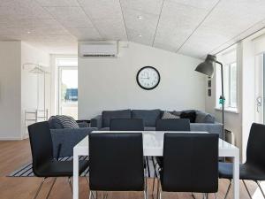 une salle à manger avec une table, des chaises et une horloge dans l'établissement 6 person holiday home in L kken, à Løkken