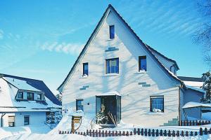 ein großes weißes Haus mit Schnee drauf in der Unterkunft Pension Haus Barbara Oberhof in Oberhof