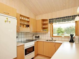 cocina con armarios de madera y nevera blanca en 6 person holiday home in Fjerritslev en Torup Strand