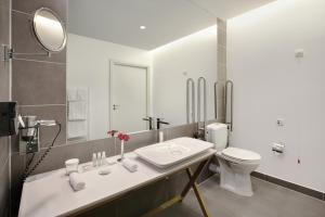 a bathroom with a toilet, sink, and mirror at Crowne Plaza Berlin - Potsdamer Platz, an IHG Hotel in Berlin