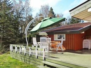 eine Terrasse mit einem Tisch, Stühlen und einem Sonnenschirm in der Unterkunft 10 person holiday home in V ggerl se in Bøtø By