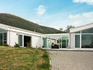 een wit huis met glazen ramen en een heuvel bij 6 person holiday home in Inndyr in Inndyr