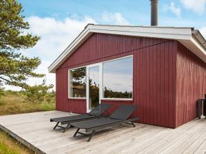 Three-Bedroom Holiday home in Rømø 35 في Bolilmark: مبنى احمر مع مقعد على سطح السفينة