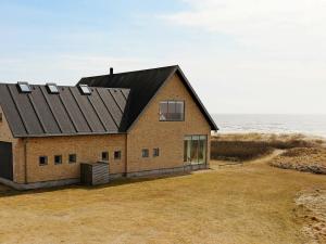 una casa de ladrillo con techo negro en la playa en 6 person holiday home in Bl vand, en Blåvand