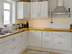 eine weiße Küche mit weißen Schränken und einem Waschbecken in der Unterkunft 5 person holiday home in DYR N in Stora Dyrön