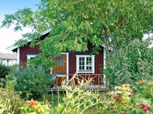 una casa roja con una ventana blanca en un jardín en Holiday Home Målaretorpsvägen, en Borgholm